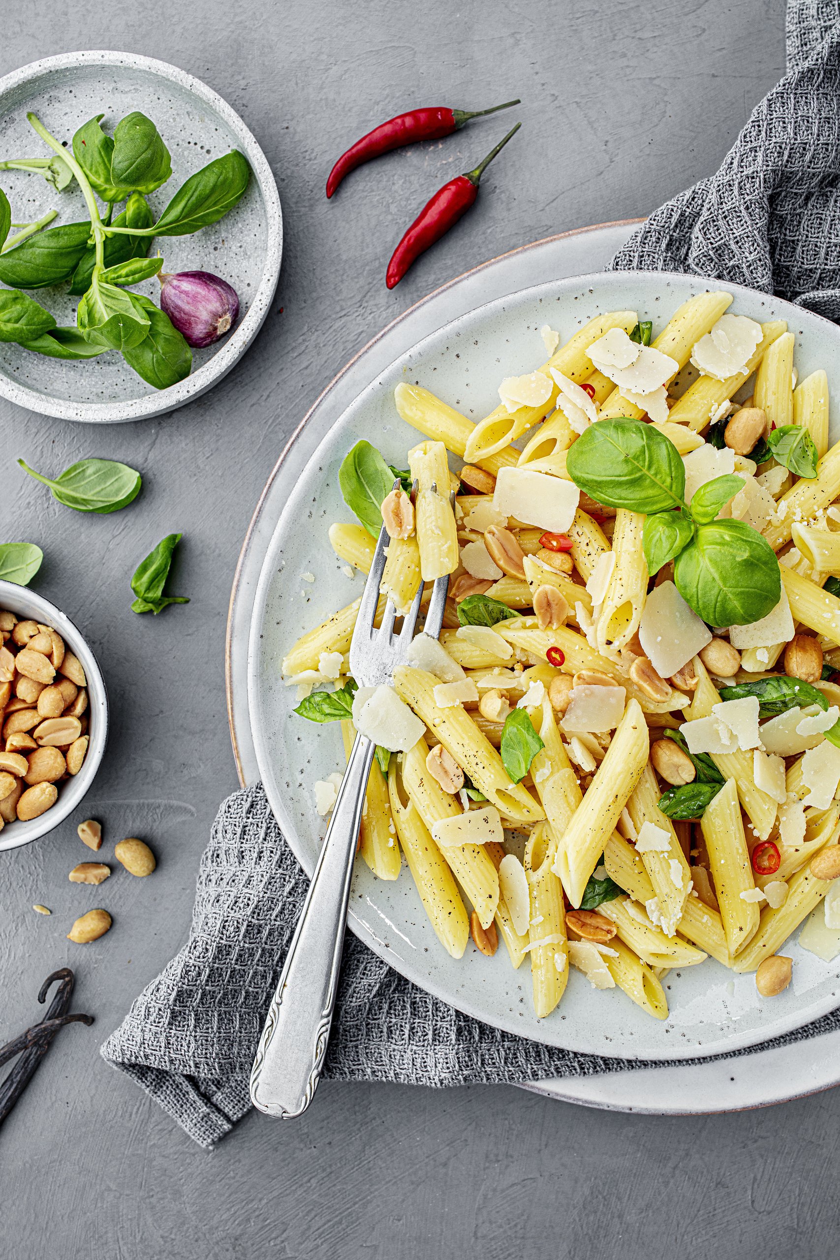 Nudeln mit Chili, Parmesan und Nüssen auf einem Teller mit frischen Kräutern