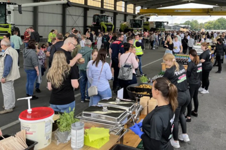 Menschen in einer Halle an der Essensausgabe von apetito catering am Familientag des Kunden Claas 