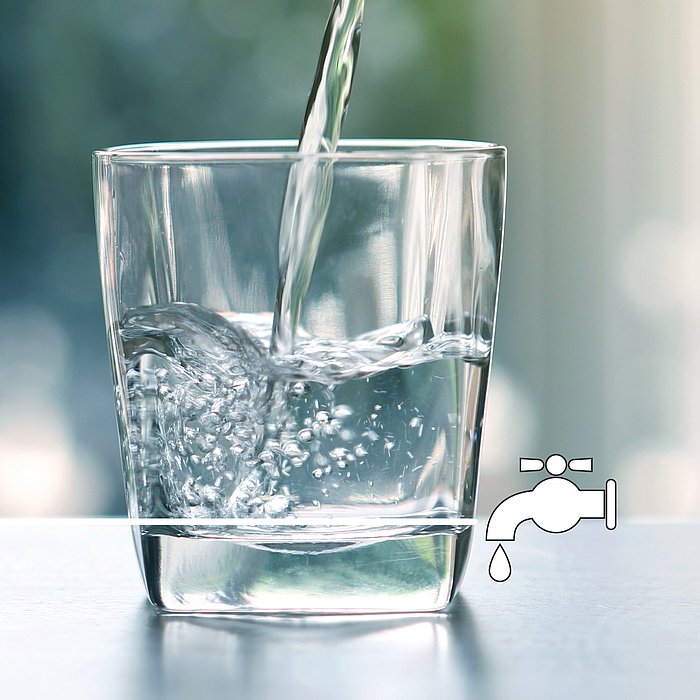 Ein Glas Wasser, welches befüllt wird. Rechts unten ein eingefügter Wasserharn, welcher tropft. 