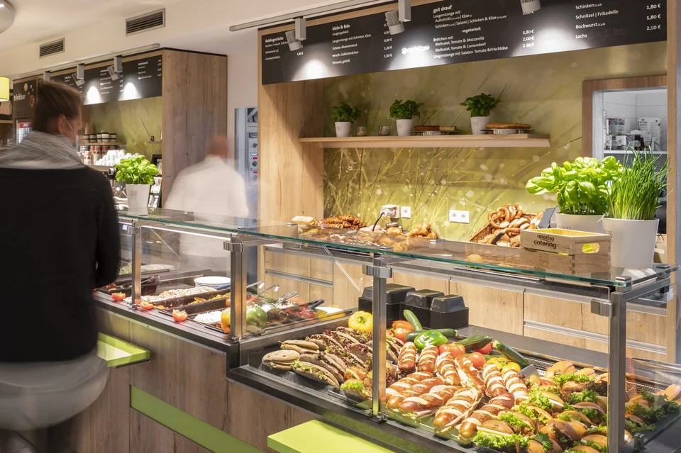 Mitarbeiter laufen durch die Ausgabe der Betriebsgastronomie